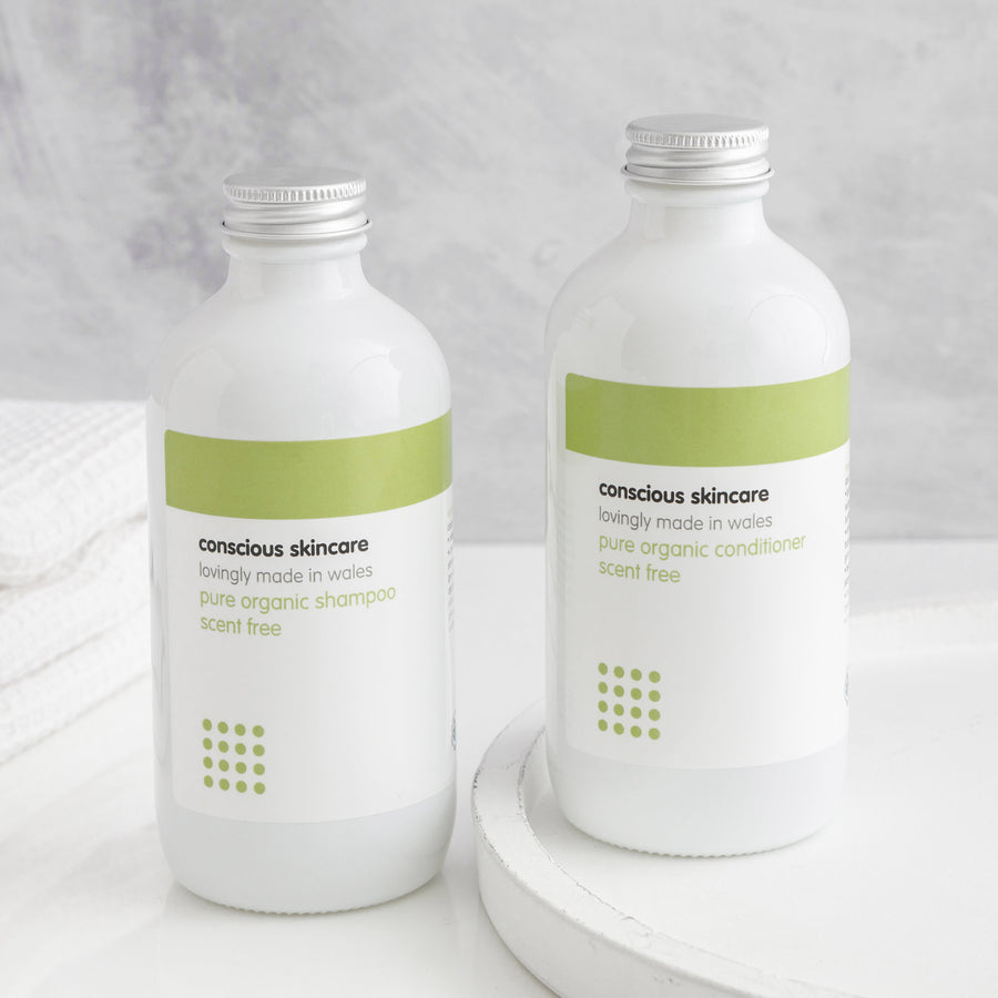 Pure Fragrance Free Shampoo and Conditioner in white glass bottles with silver caps on white table