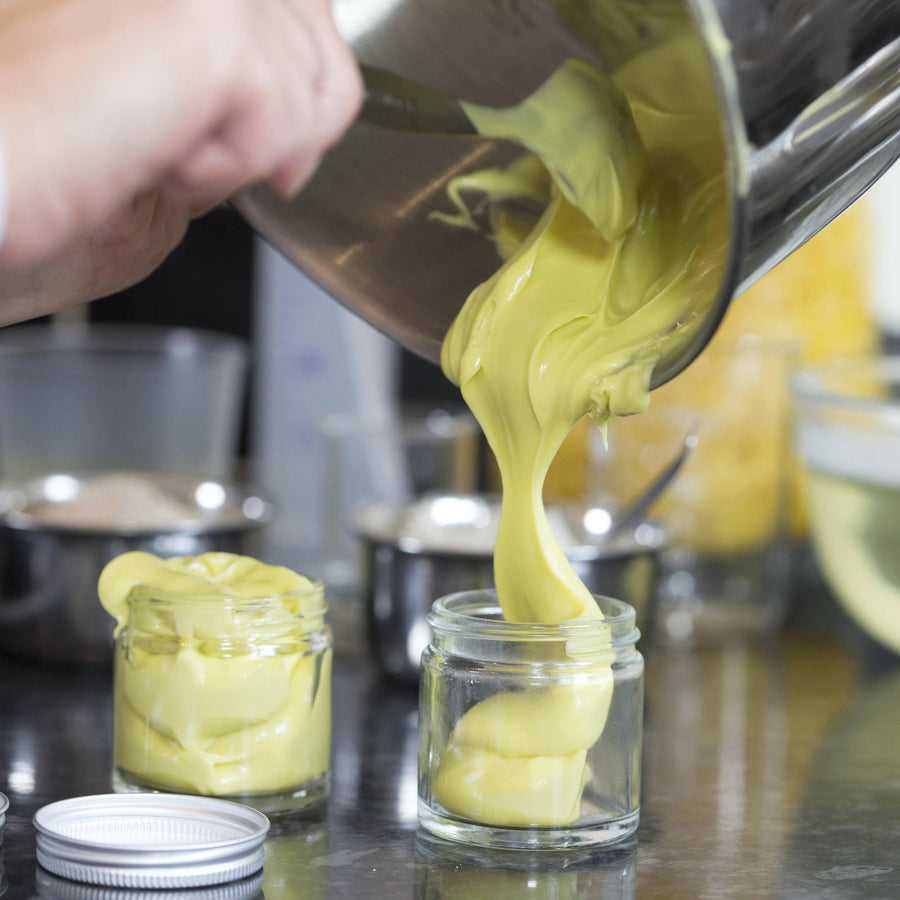 Rich vegan hand cream being poured into clear glass jar