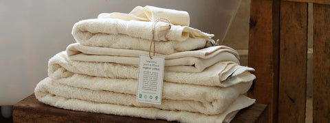 Organic towels piled on top of a rustic wooden stool with certified organic label