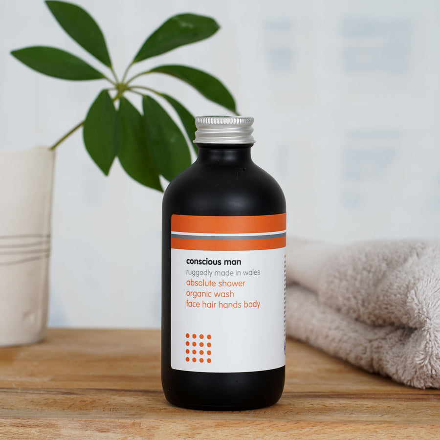 Absolute Men’s organic shower gel on a wooden table with towel and plant