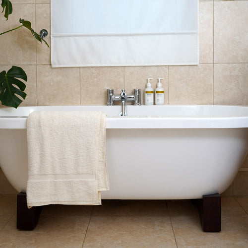 luxury bath towel made with organic cotton on white bath in bathroom