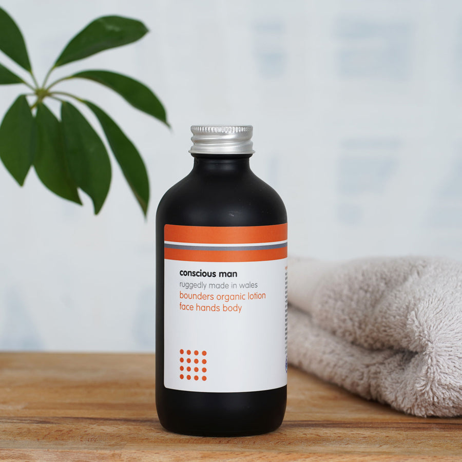 Bounders men’s body moisturiser on a wooden table with towel and plant