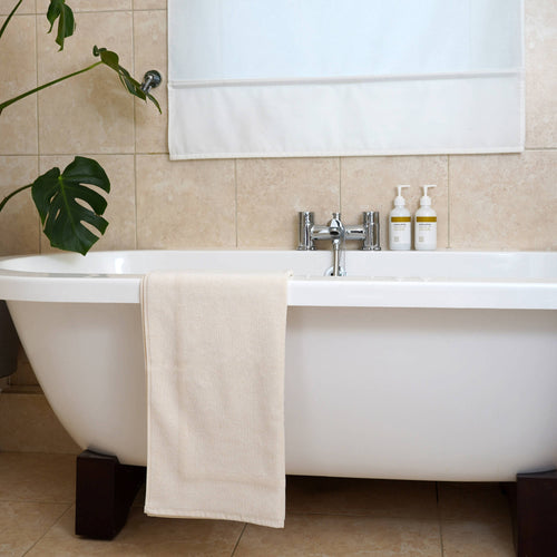 natural bath mat made from organic cotton placed on white luxury bath