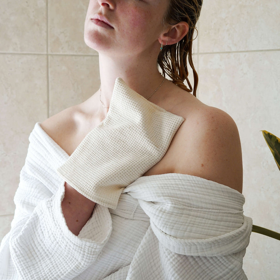 organic cotton facial mitt placed on womans chest and neck