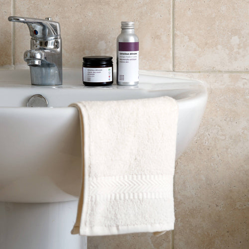 luxury hand towel made with organic cotton hanging on white sink  in bathroom