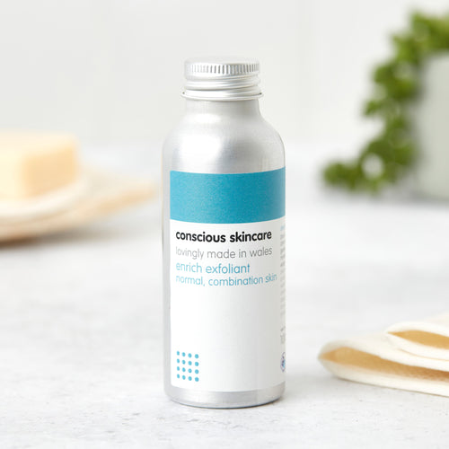 Natural face exfoliator in silver aluminium bottle with screw cap on white table